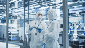 Industrial Scientists Wearing Disposable Protective Suits, Masks, and Goggles at a Production Plant