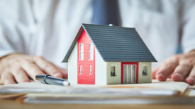 Model of a home on top of insurance paperwork